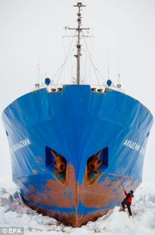 A crew member inspects the hull of the ship